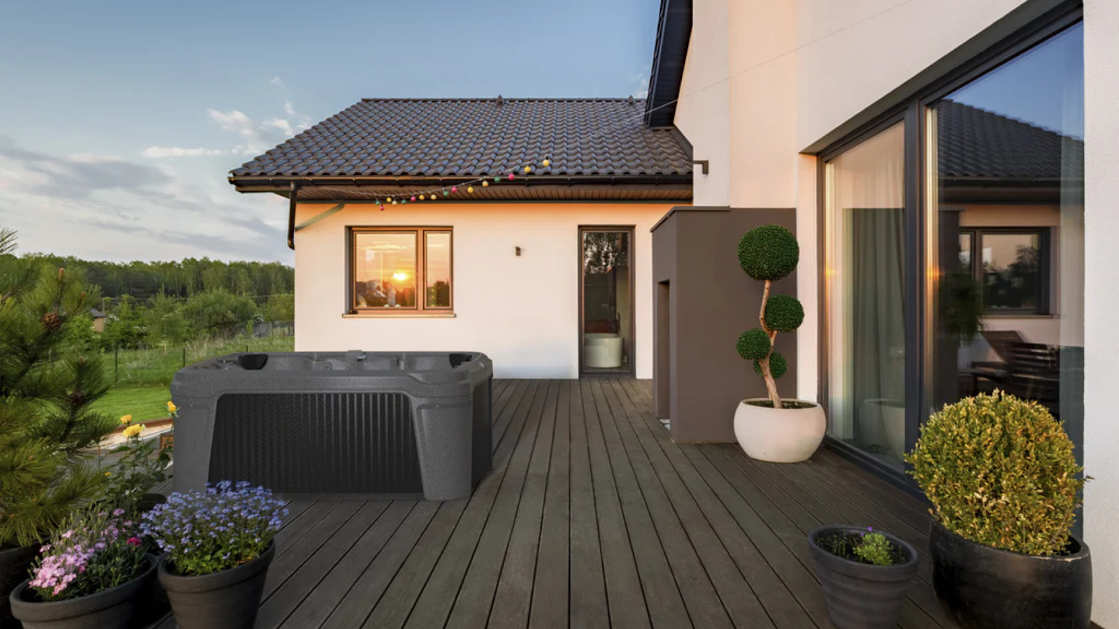 Outdoor hot tub on a modern backyard deck beside a contemporary home at sunset